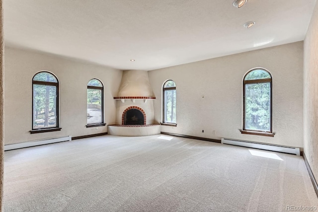 unfurnished living room featuring a fireplace, a baseboard heating unit, and carpet floors