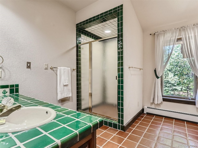 full bath with a sink, a baseboard radiator, a shower stall, and tile patterned floors