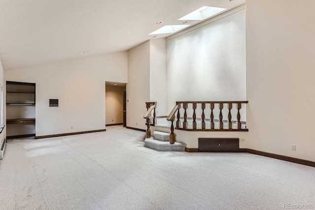 unfurnished room featuring baseboards, carpet, a skylight, and high vaulted ceiling