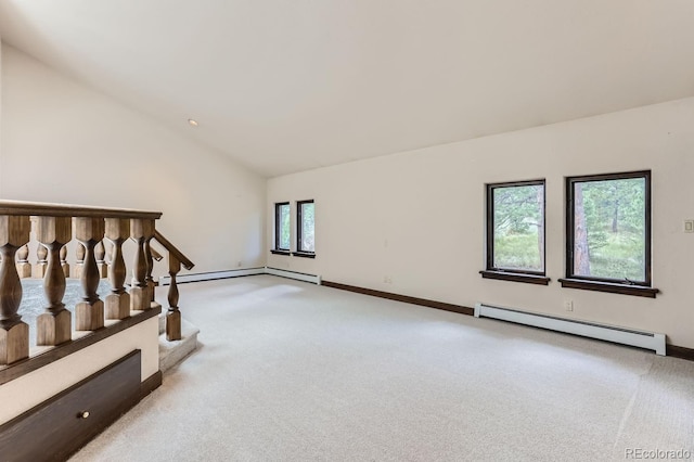 empty room featuring baseboard heating, light colored carpet, and vaulted ceiling