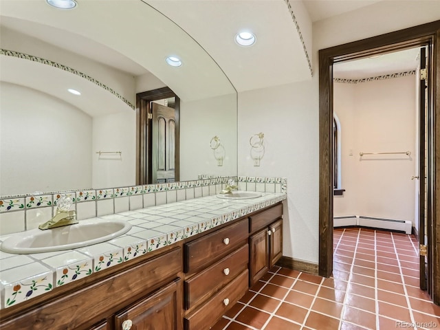 full bath with a baseboard heating unit, tile patterned floors, double vanity, and a sink