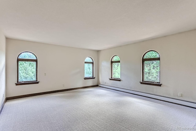 spare room featuring baseboard heating, baseboards, and carpet