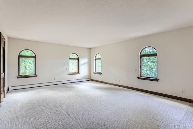 unfurnished room with baseboard heating, baseboards, and carpet