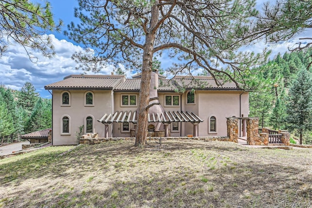 back of house featuring stucco siding and a tile roof