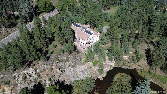 birds eye view of property with a wooded view and a water view