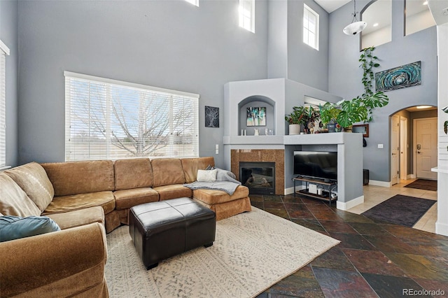 11307 Navajo Cir Unit A, Westminster, CO 80234 - living area featuring a towering ceiling, arched walkways, stone tile flooring, and a fireplace