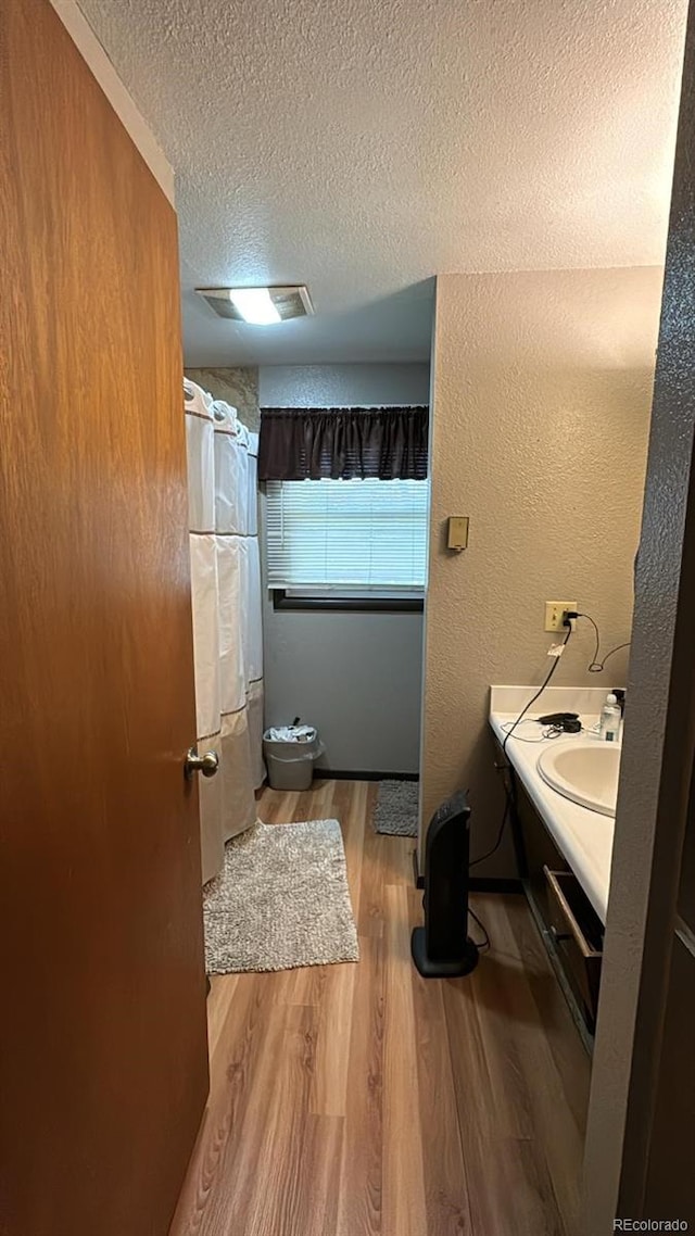 bathroom with hardwood / wood-style flooring, toilet, a shower with curtain, vanity, and a textured ceiling