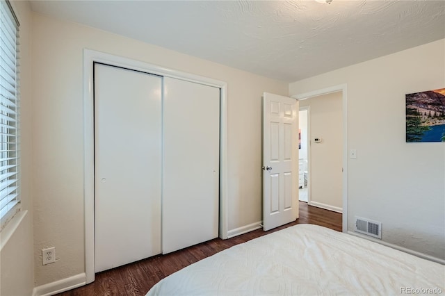 bedroom with dark hardwood / wood-style floors and a closet