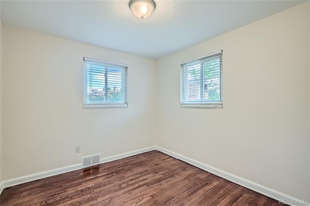 empty room with dark wood-type flooring and a wealth of natural light