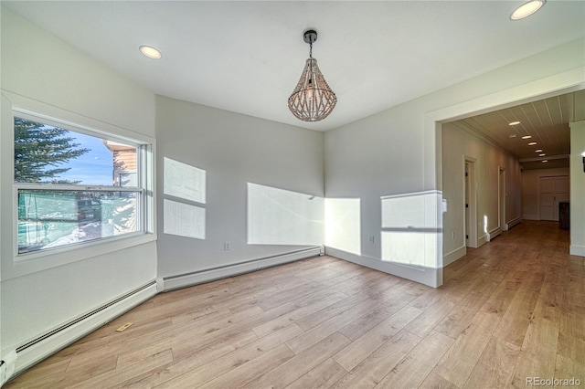 spare room with a chandelier, a baseboard radiator, and light hardwood / wood-style flooring