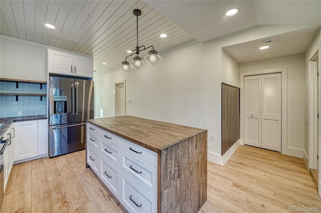 kitchen featuring decorative backsplash, high end refrigerator, white cabinetry, and hanging light fixtures