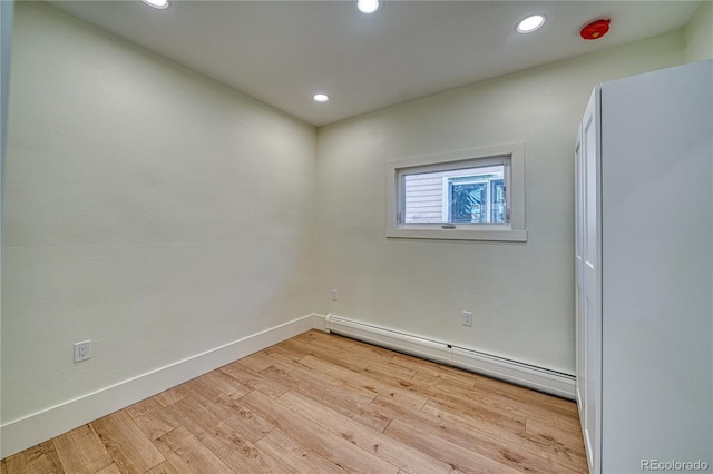 empty room with light hardwood / wood-style flooring and a baseboard radiator