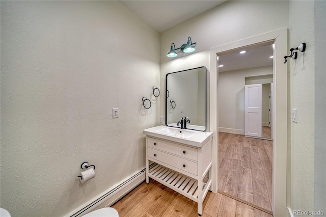 bathroom featuring hardwood / wood-style floors, vanity, and a baseboard radiator