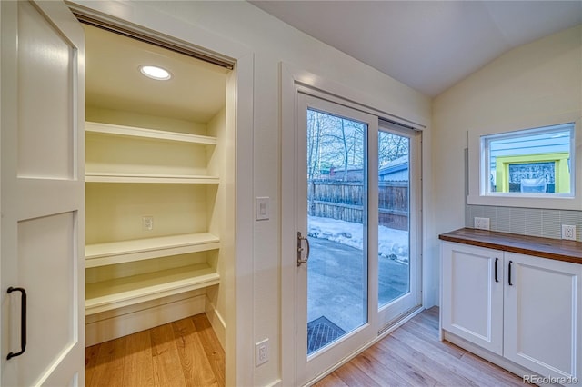 doorway featuring built in shelves, light hardwood / wood-style flooring, and lofted ceiling