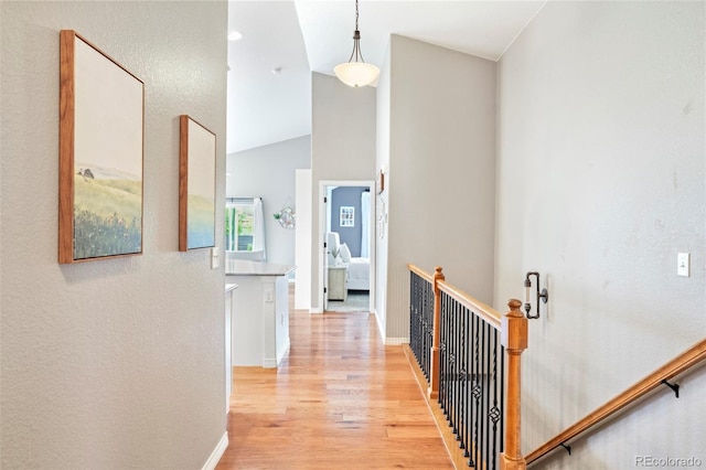 577 Tristan Pl, Berthoud, CO 80513 - hall featuring light wood-type flooring, vaulted ceiling, baseboards, and an upstairs landing