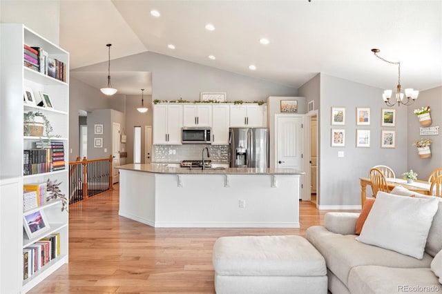 577 Tristan Pl, Berthoud, CO 80513 - kitchen with stainless steel appliances, a sink, open floor plan, light wood-style floors, and a breakfast bar