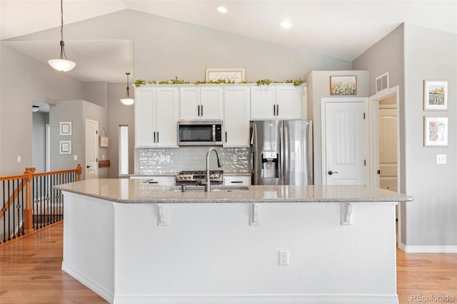 577 Tristan Pl, Berthoud, CO 80513 - kitchen featuring stainless steel appliances, lofted ceiling, light wood finished floors, a breakfast bar, and light stone counters