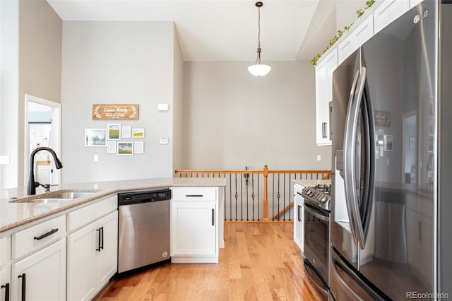 577 Tristan Pl, Berthoud, CO 80513 - kitchen with stainless steel appliances, a sink, light wood-style floors, white cabinetry, and lofted ceiling