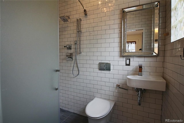 bathroom featuring toilet, a tile shower, sink, and tile walls