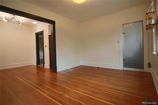 empty room with a chandelier and hardwood / wood-style flooring