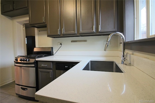 kitchen with sink, light tile patterned flooring, dark brown cabinets, and stainless steel range with gas stovetop