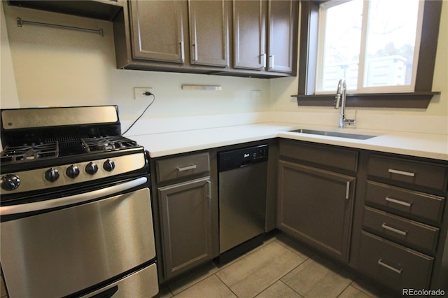 kitchen featuring dark brown cabinetry, light tile patterned floors, sink, and appliances with stainless steel finishes