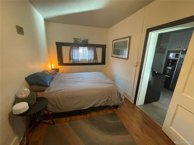 bedroom featuring black fridge and wood-type flooring