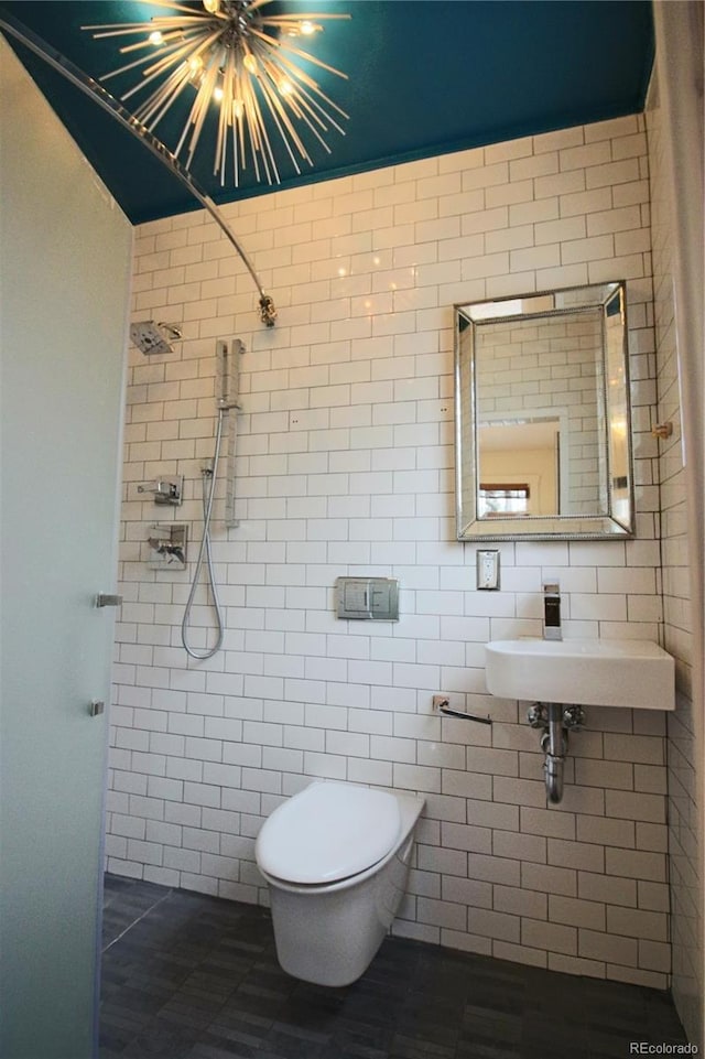 bathroom with toilet, sink, an inviting chandelier, and walk in shower