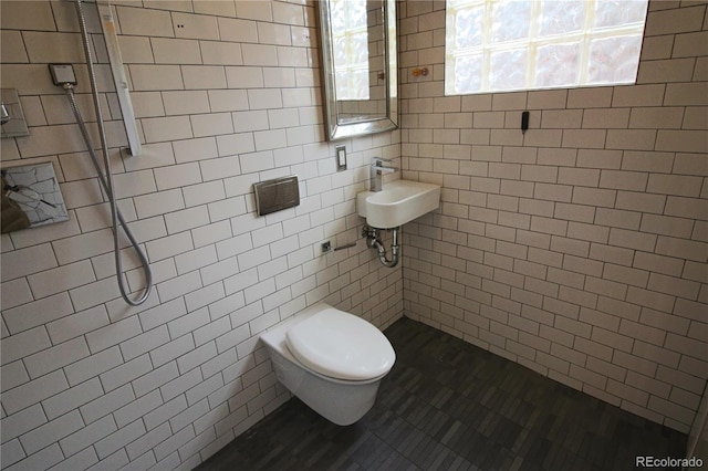 bathroom featuring tiled shower, sink, tile walls, and toilet