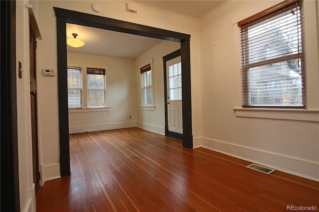 unfurnished room with crown molding, plenty of natural light, and dark hardwood / wood-style floors