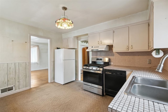 305 W Brookside St, Colorado Springs, CO 80905 - kitchen with freestanding refrigerator, gas stove, under cabinet range hood, tile counters, and black dishwasher