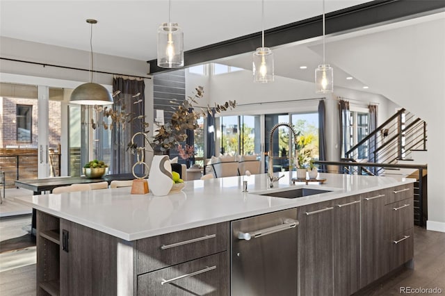 kitchen with sink, hanging light fixtures, dark brown cabinets, an island with sink, and dark hardwood / wood-style flooring