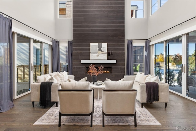 living room with a towering ceiling, a fireplace, and dark hardwood / wood-style flooring