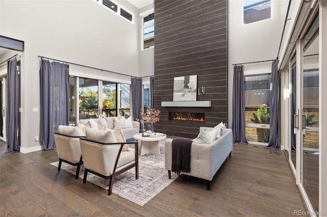 living room with a large fireplace, dark hardwood / wood-style floors, and a towering ceiling