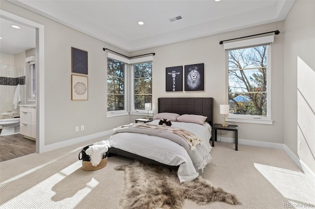 bedroom with ensuite bathroom and carpet floors