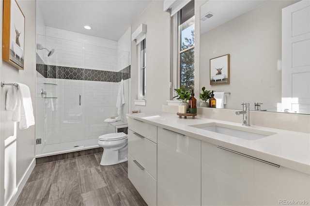 bathroom featuring vanity, hardwood / wood-style floors, a shower with shower door, and toilet