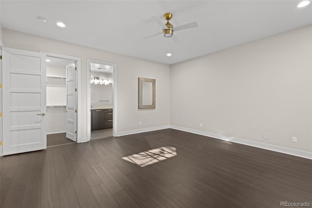 unfurnished bedroom featuring dark wood-type flooring, ensuite bath, a spacious closet, a closet, and ceiling fan