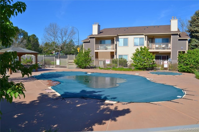 community pool featuring fence, a patio, and a gazebo
