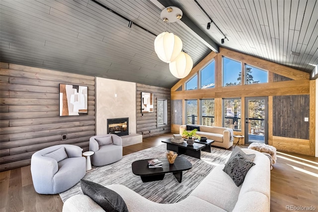 living room featuring a large fireplace, log walls, track lighting, high vaulted ceiling, and wood-type flooring