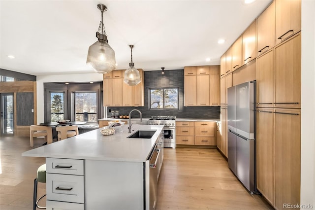 kitchen with appliances with stainless steel finishes, hanging light fixtures, an island with sink, a kitchen bar, and sink