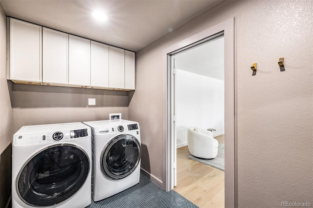 clothes washing area featuring independent washer and dryer, cabinets, and light hardwood / wood-style flooring