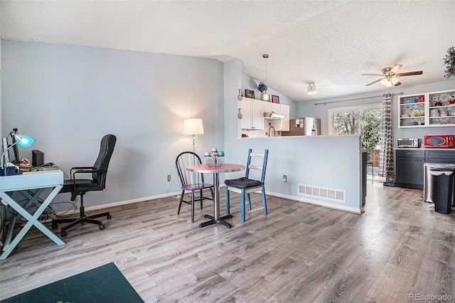 dining space with visible vents, ceiling fan, light wood-type flooring, a textured ceiling, and vaulted ceiling