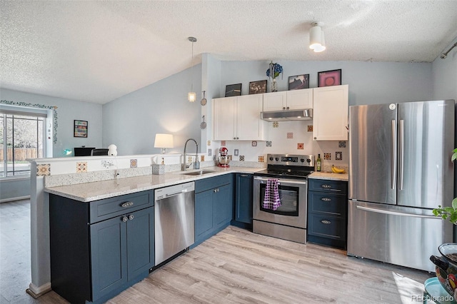 kitchen featuring appliances with stainless steel finishes, a sink, a peninsula, under cabinet range hood, and vaulted ceiling