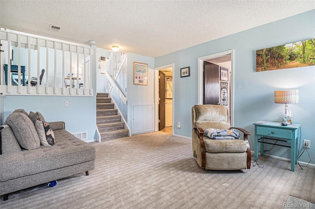 carpeted living room with a textured ceiling, baseboards, visible vents, and stairway