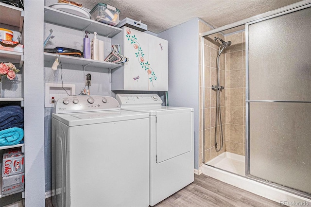 laundry room featuring separate washer and dryer, laundry area, light wood finished floors, and a textured ceiling