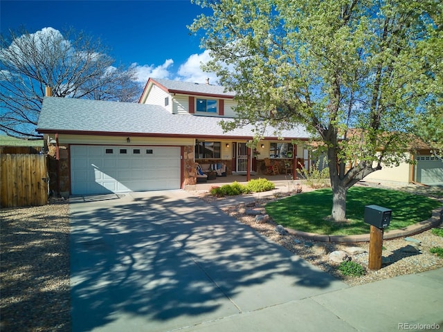 traditional-style house featuring fence, stone siding, a garage, a porch, and driveway