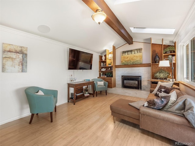 living area featuring baseboards, a high end fireplace, light wood finished floors, and lofted ceiling with skylight
