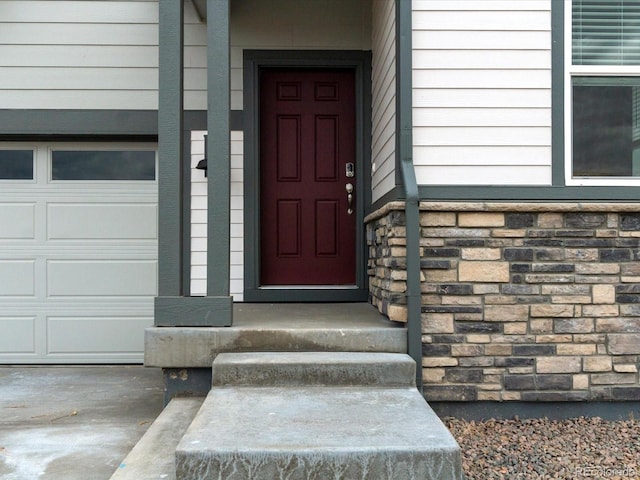 doorway to property featuring stone siding and a garage