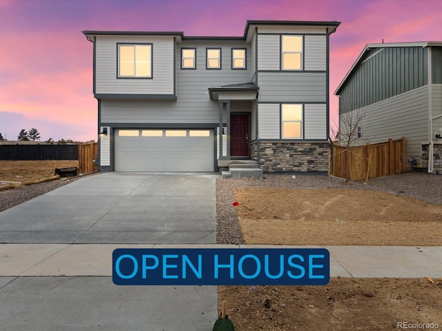 contemporary home featuring stone siding, concrete driveway, fence, and an attached garage