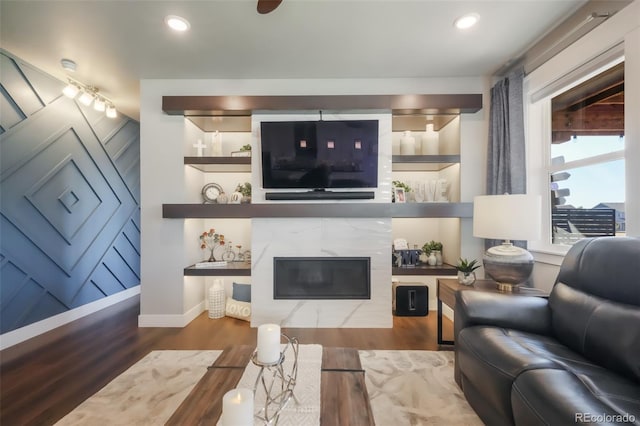 living area with built in features, recessed lighting, a premium fireplace, wood finished floors, and baseboards